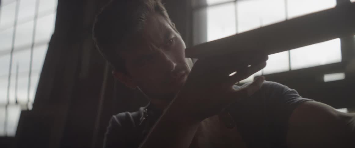 A man is blowing sawdust off of a piece of wood he is examining