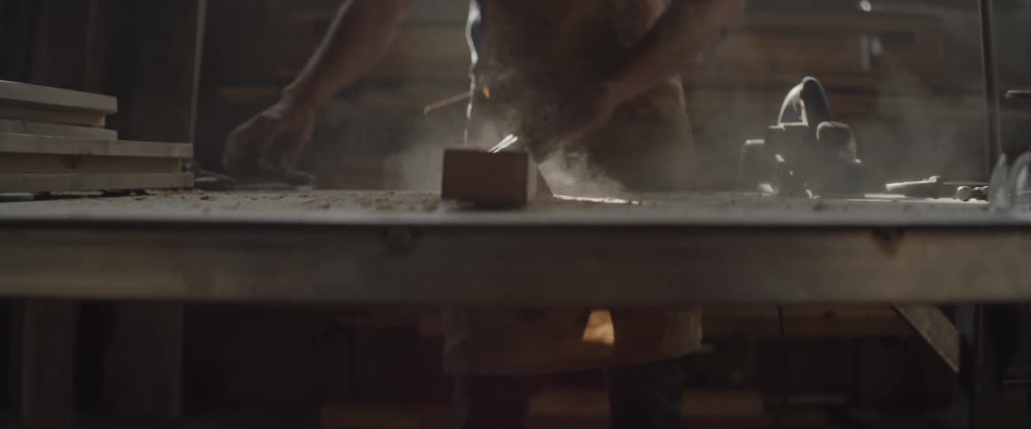 A man slams a piece of wood on the bench