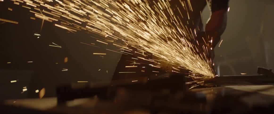 Sparks fly around a welder in a workshop