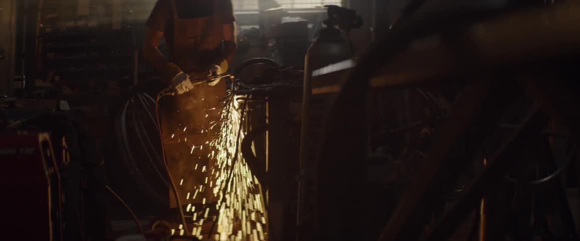 A man is welding in the dark garage