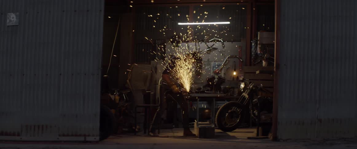 A man grinds steel in a workshop