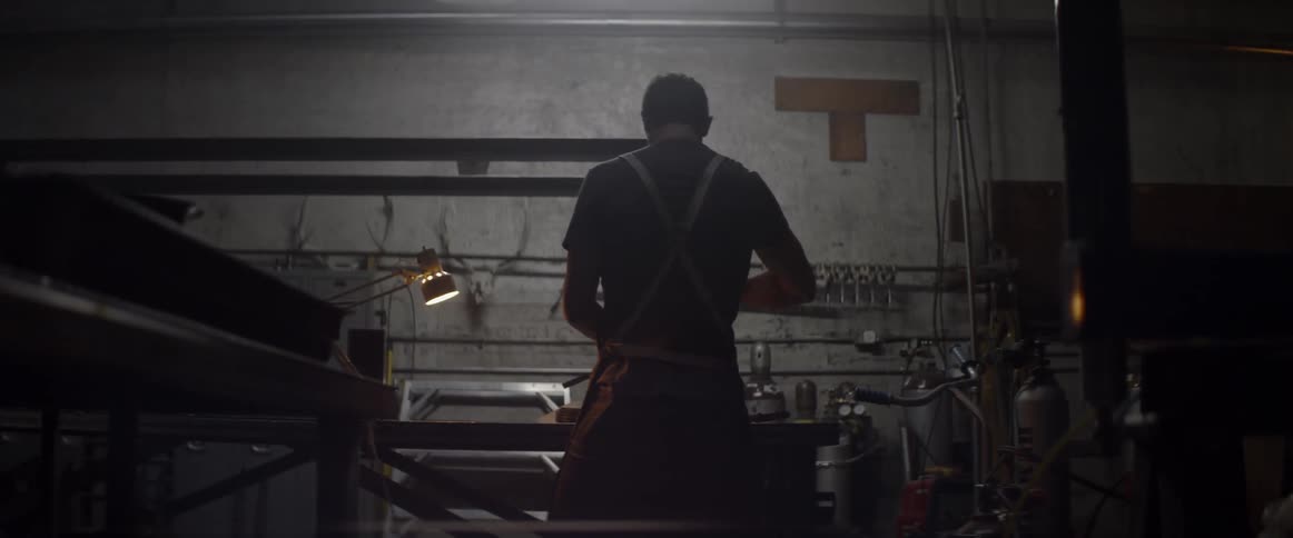 A man in a workshop stands at a work bench