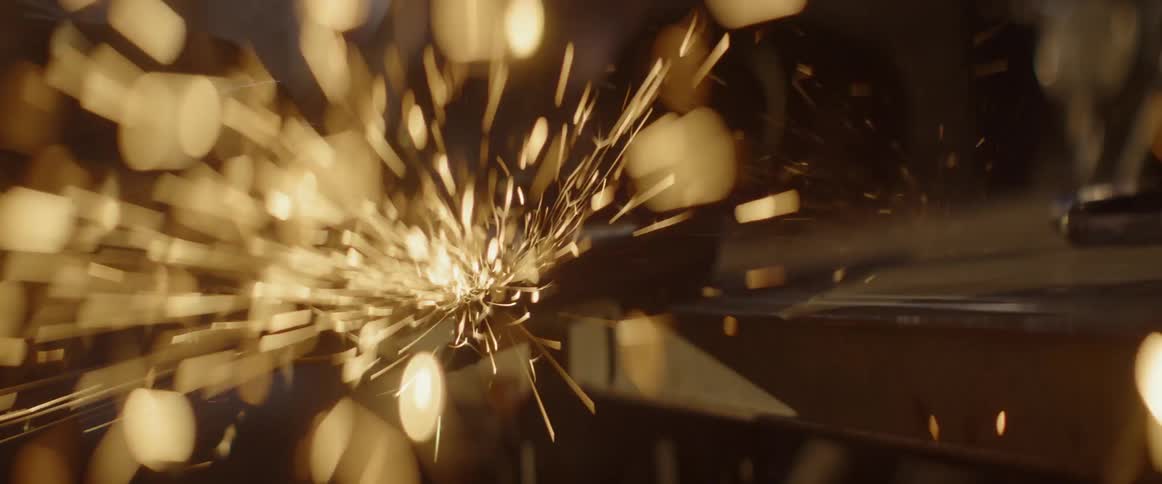Sparks are flying from a grinder as it is moved across a piece of metal