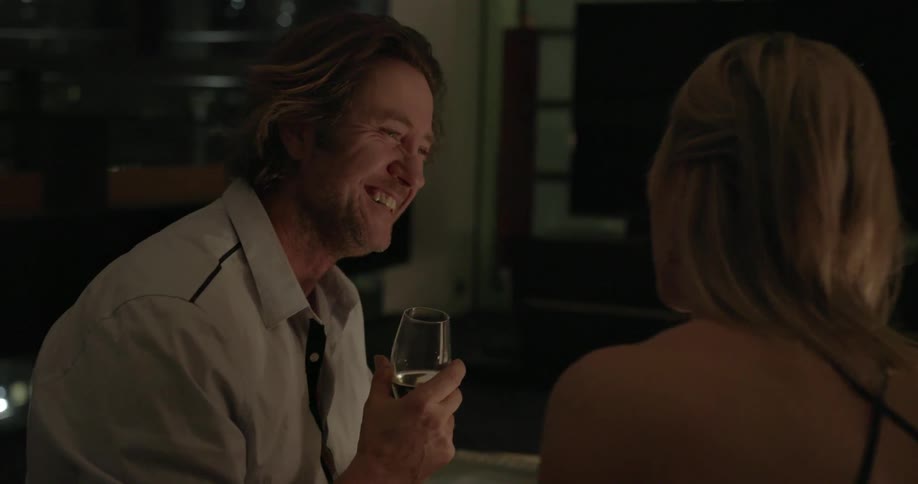 Man and woman talk and laugh at a dinner table while holding wine glasses