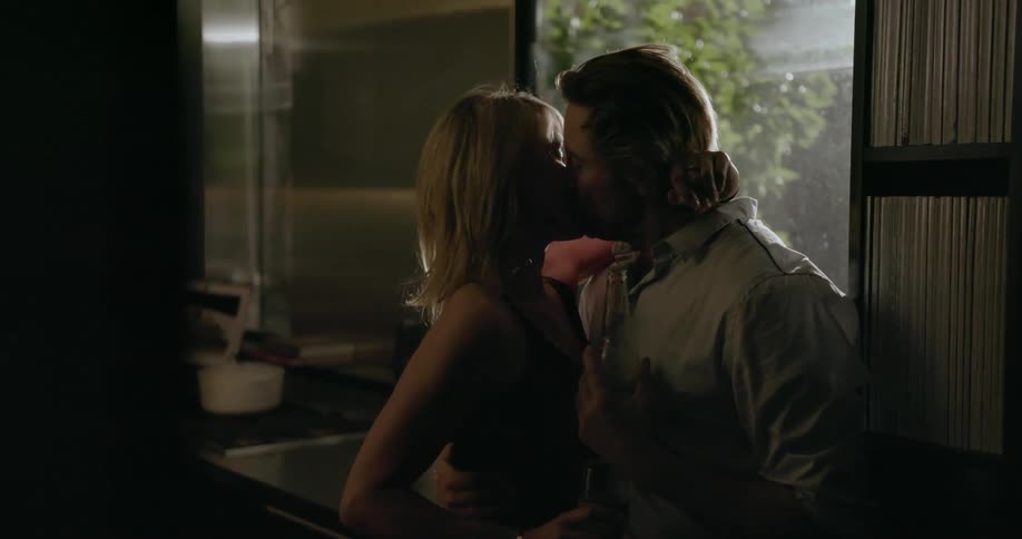 A man and woman kiss in a kitchen