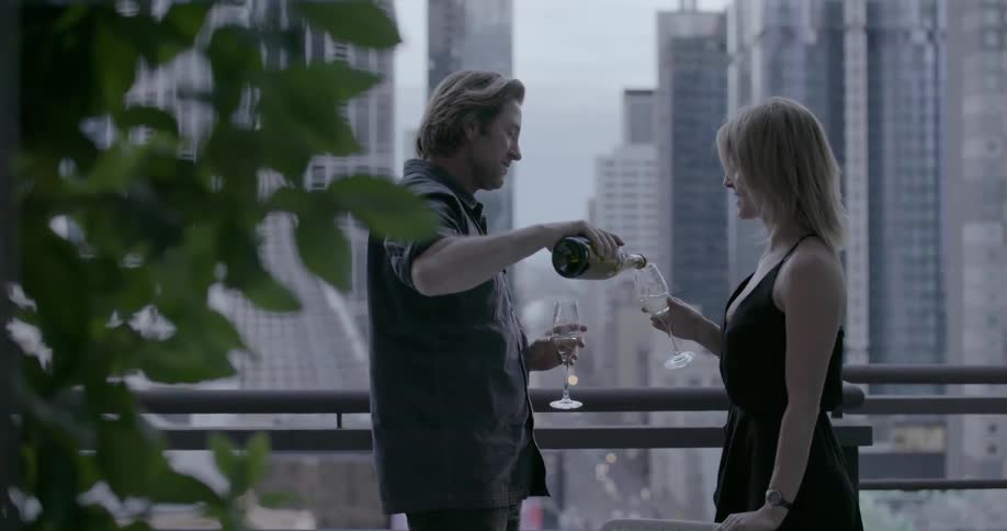 A man pours champagne for his date on a balcony