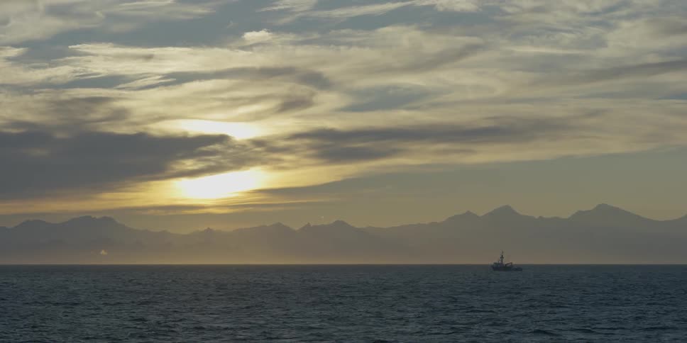 A boat is off a coast as the sun is rising