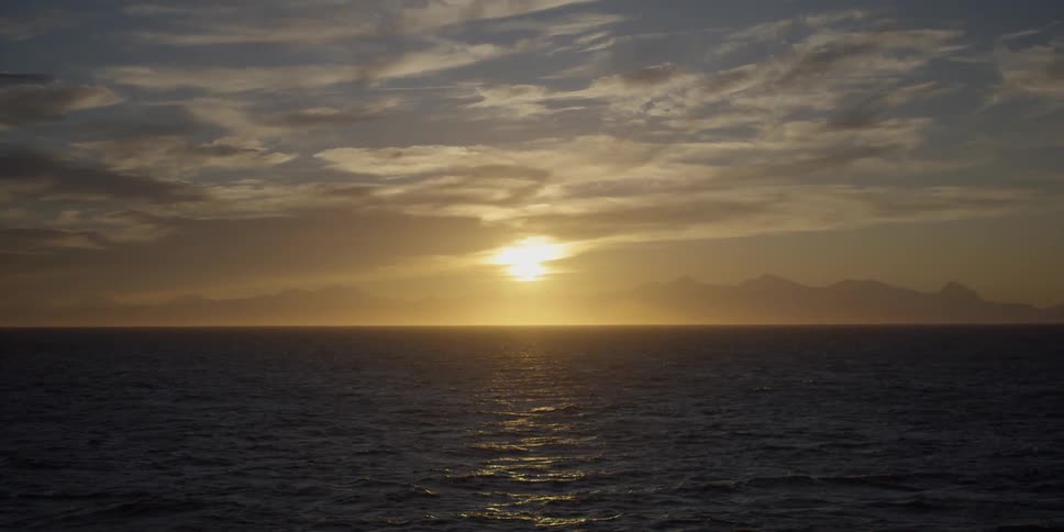The sun sets on the horizon over the ocean