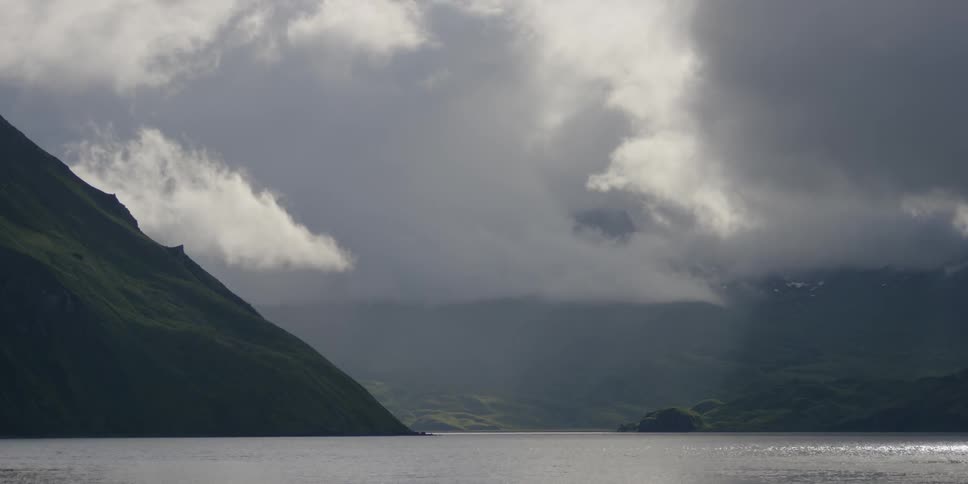 The ocean water is calm near the mountains