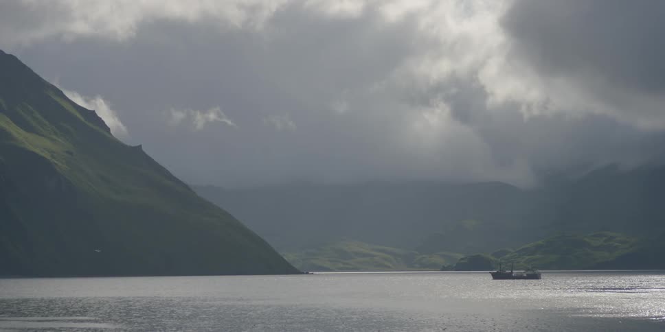 A boat travels on the water between mountains