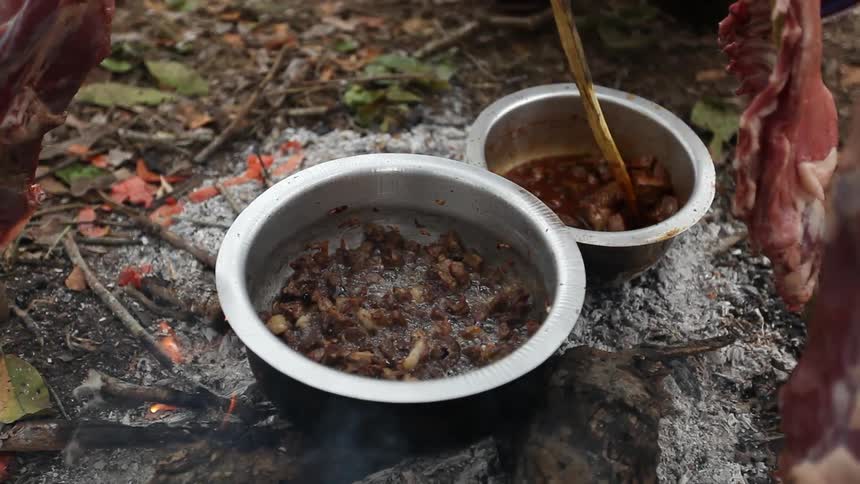 Food cooking in bowls on a campfire