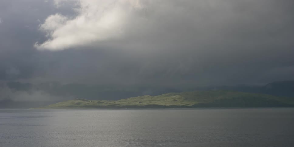 Storm clouds hang above the water and coast