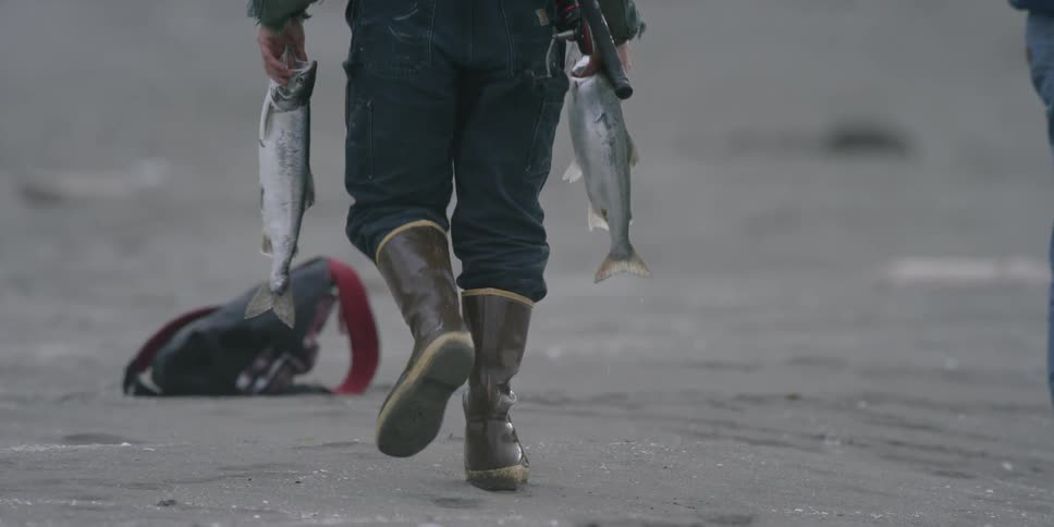 A fisherman carries two caught fish
