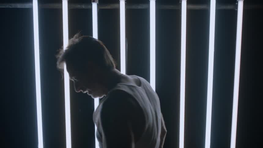 A man walks past striped lights along the wall