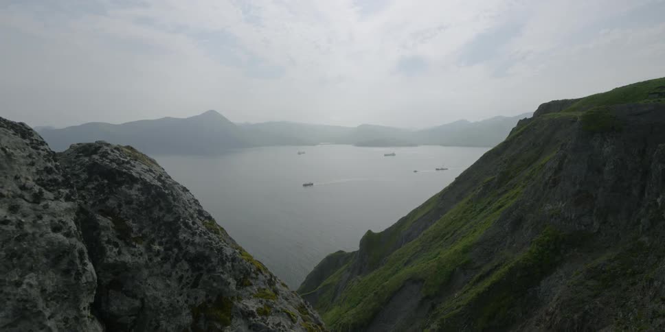 Boats travel in the water by tall mountains