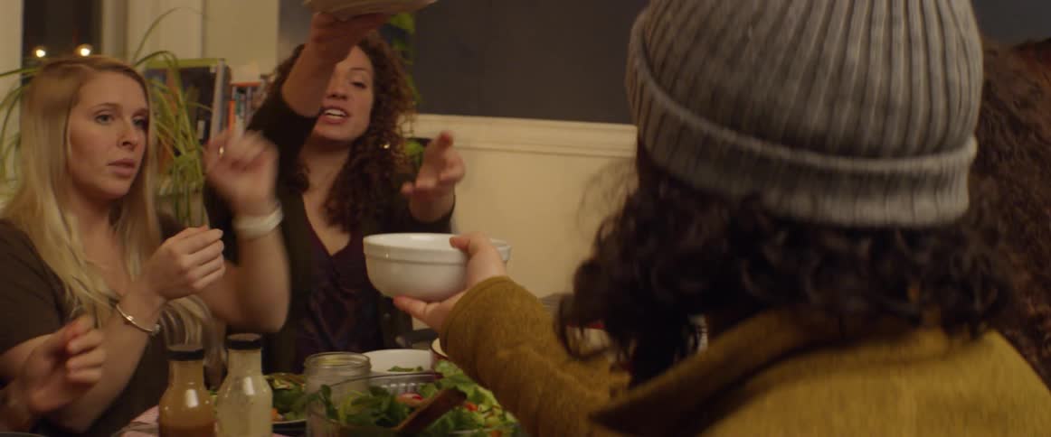 Friends pass bowls and plates around the dinner table