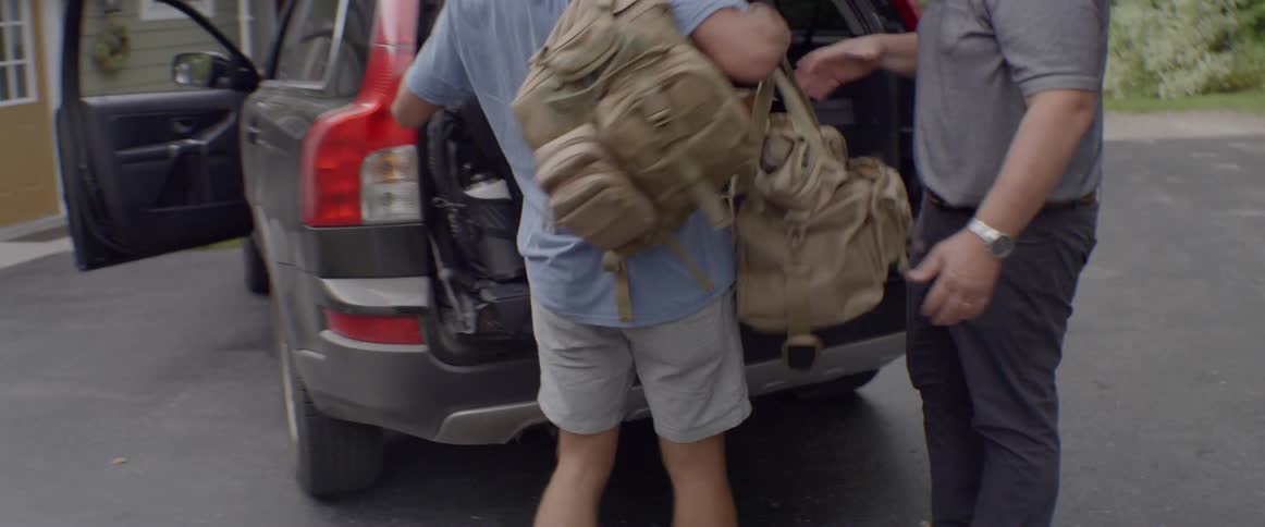 A young man carries luggage to his car