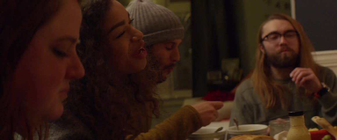 A group of friends is sharing food at a dinner table at night