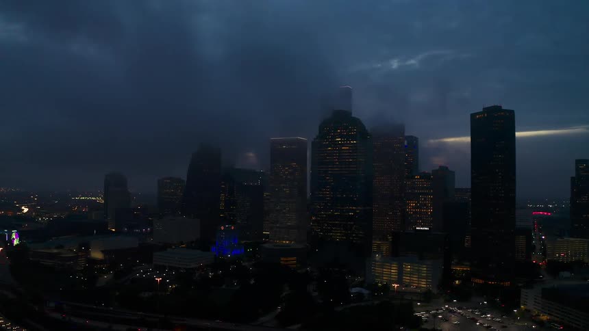 Fog hangs above and between tall city buildings