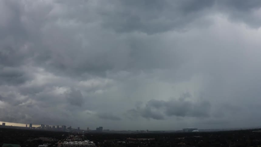 Storm clouds with lightning are moving across a city at dusk
