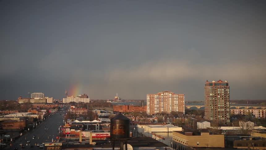 View of a busy city with part of a rainbow in the sky