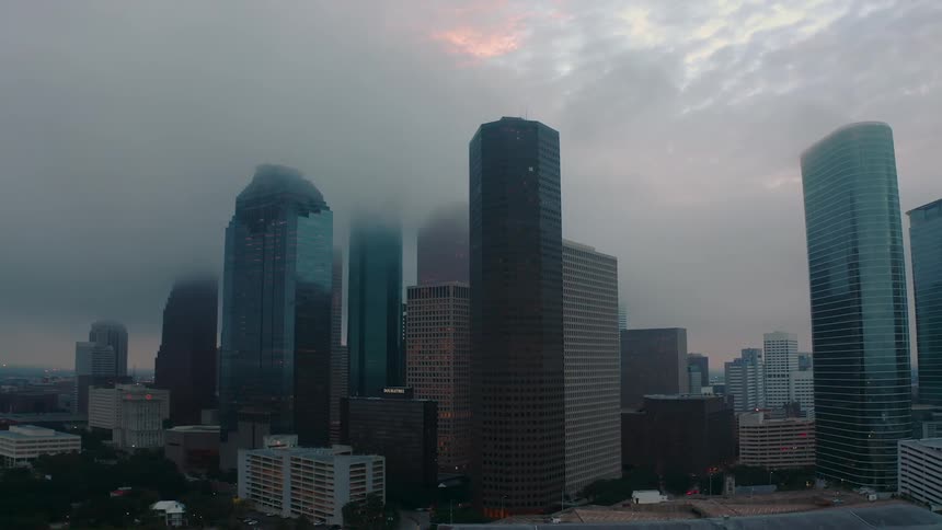 Fog hangs above and between tall city buildings