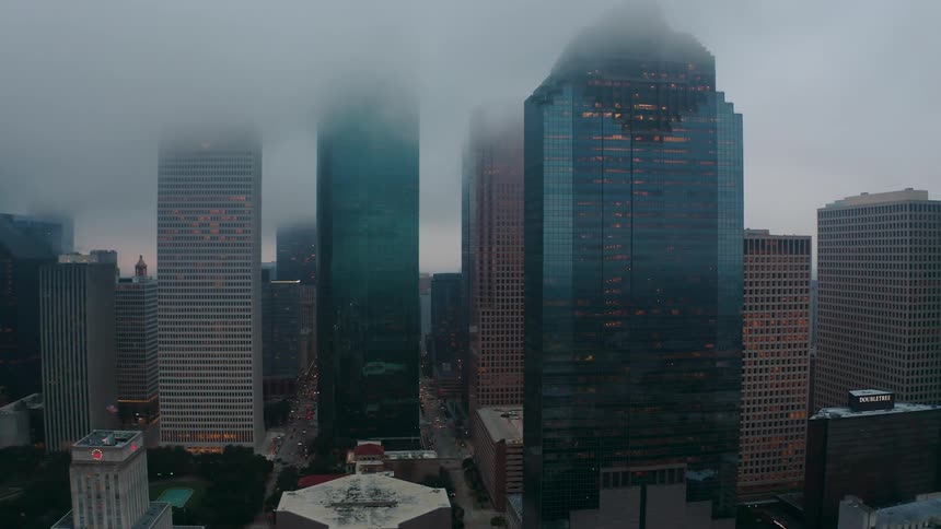 Fog hangs above and between tall city buildings