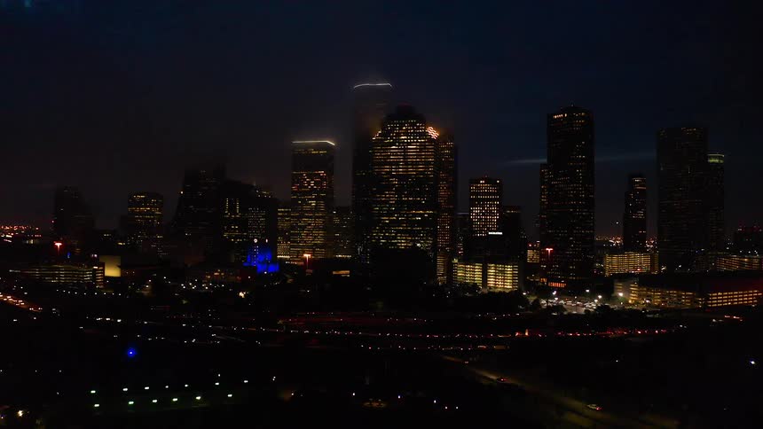 Traffic is flowing on a freeway in an urban area at night