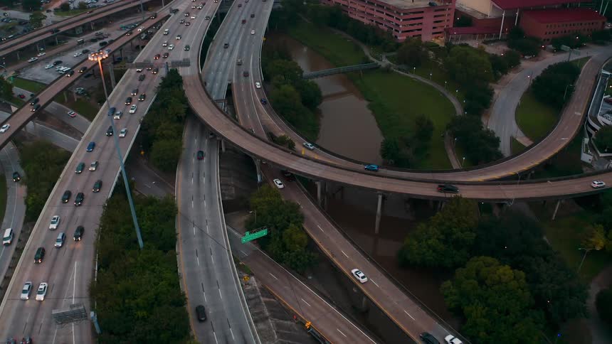 Traffic is flowing along a freeway system in a city on a cloudy day