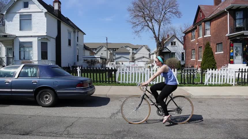 A woman bicycles on a residential road