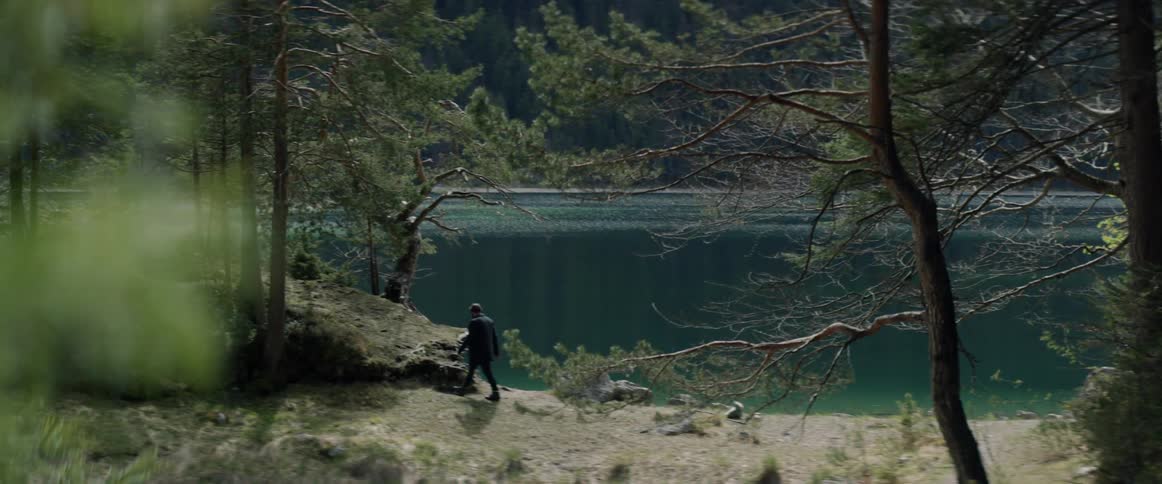 A man walks by the shore of a lake