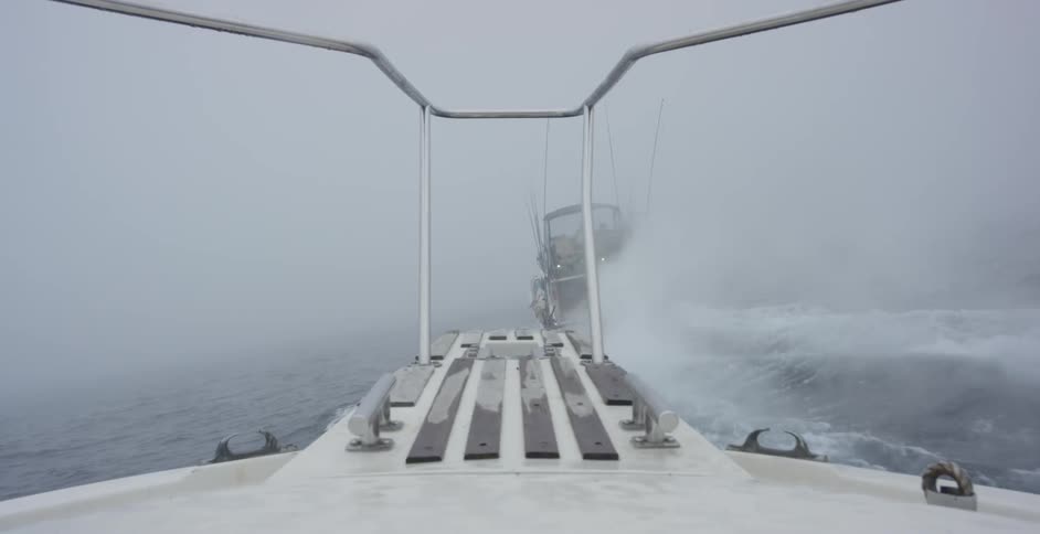 A boat moving on a foggy ocean with another boat in front of it