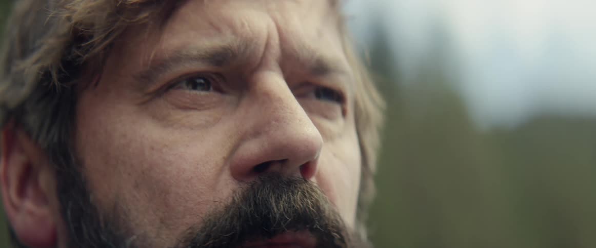 A bearded man looks around outside