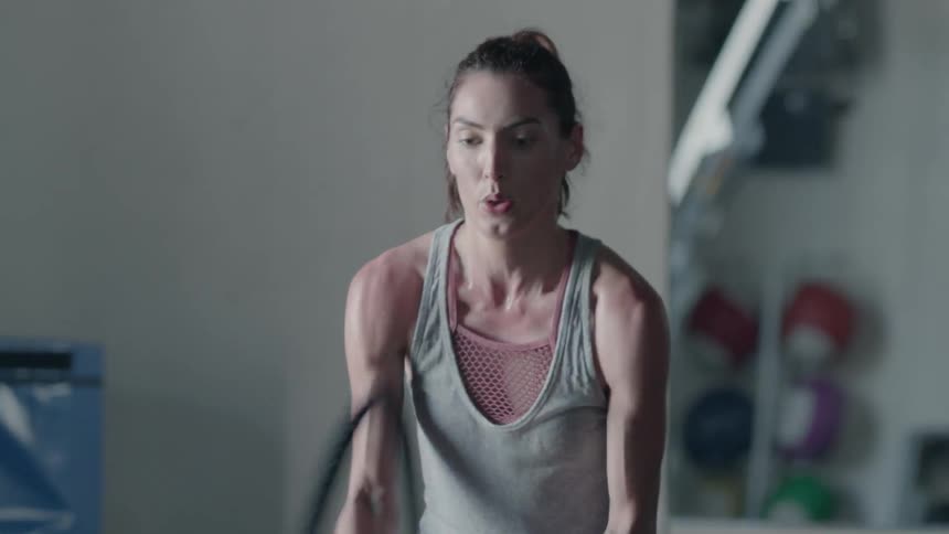 Woman exercises by hitting ropes on the floor