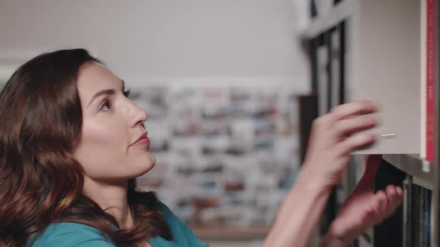 A woman is getting a binder down from a shelf