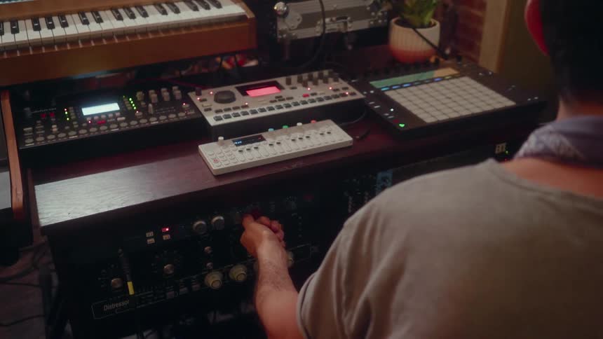 A musician records in a studio with electronic equipment