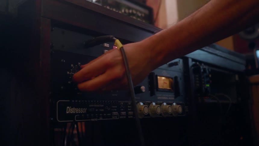 A man is adjusting the settings on a gain control unit in a studio