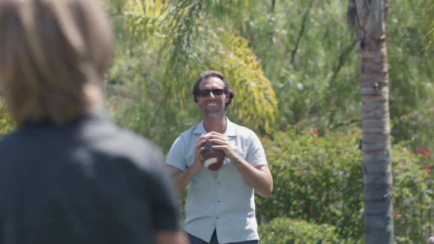 A man is tossing a football with a boy in a backyard on a sunny day