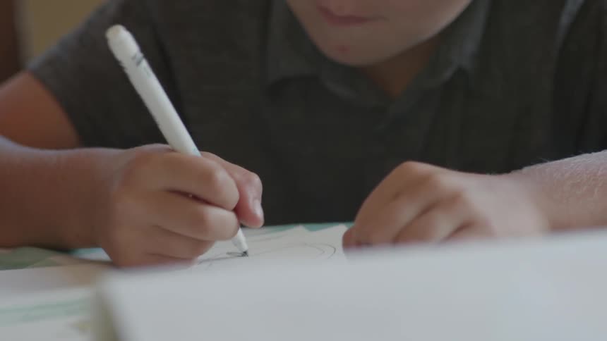 A young boy draws with markers