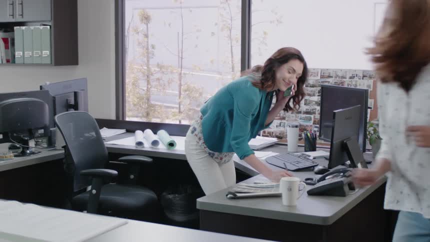 A woman is talking on the phone in an office during the day