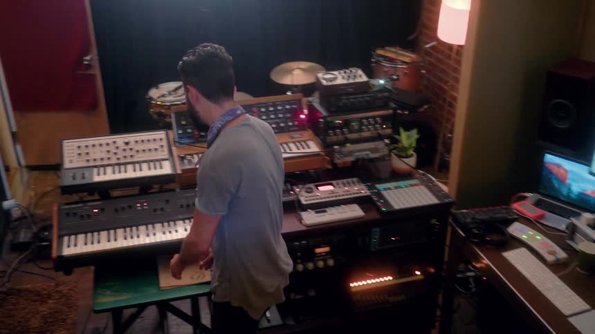 A musician records in a studio with electronic equipment