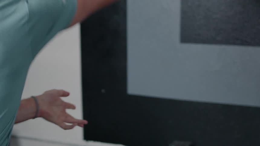 A man is throwing a weight ball against a wall in a gym during the day