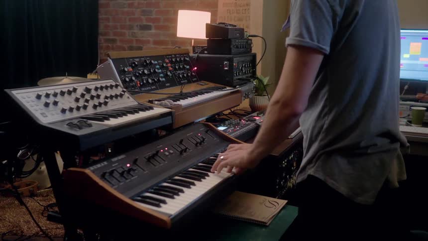 A musician records in a studio with electronic equipment