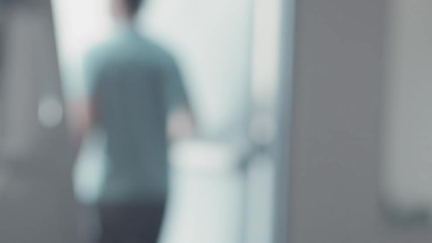 A man in a gym is standing up and walking out of the door during the day