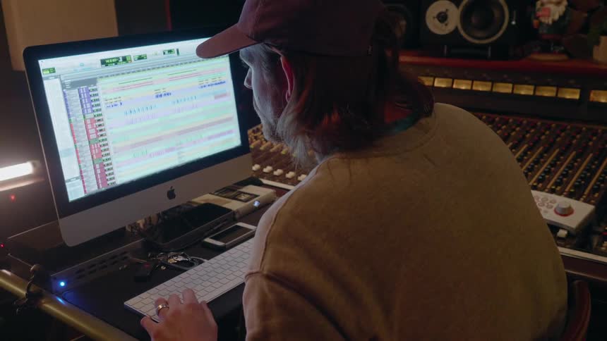 A man edits a recording in a recording studio