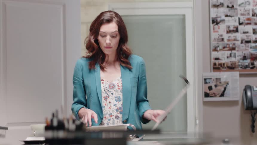 A woman carries a book over to a table