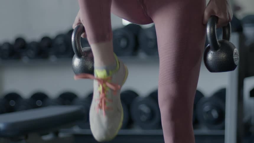 A woman is using kettlebells as she works out in a gym