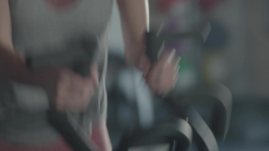 A woman is riding a stationary bike in a gym during the day