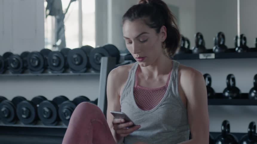 A woman grabs her phone in a gym