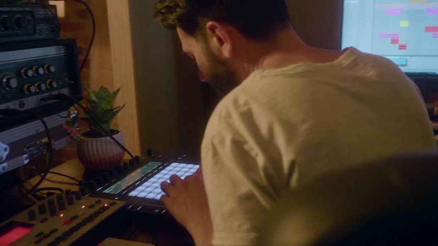 Man sits in front of electronic equipment tapping on a monitor